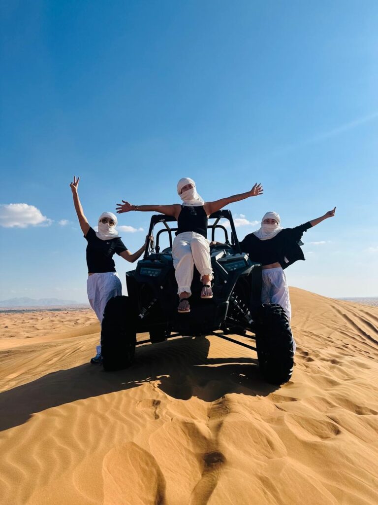 Three people donning white masks maneuver an ATV through the desert, highlighting a thrilling outdoor experience.