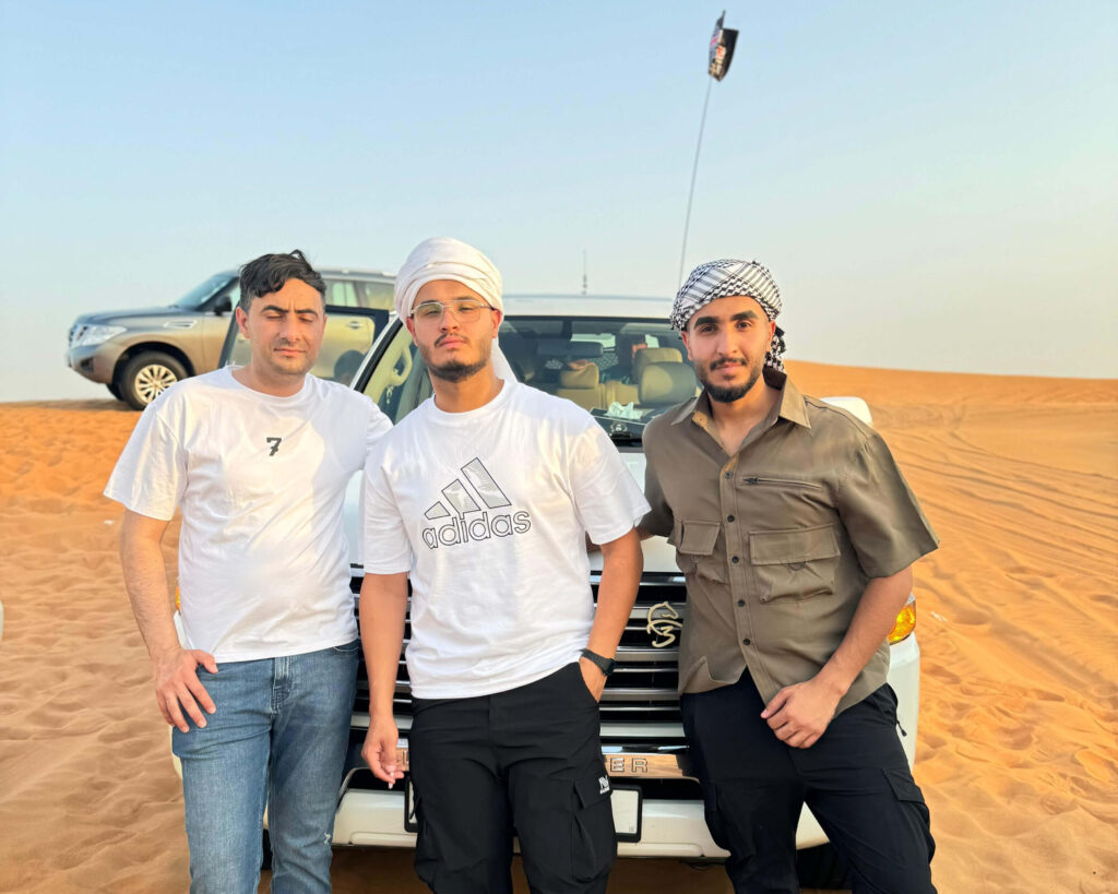 After enjoying morning desert safari & dune bashing three men standing next to a white suv in the desert