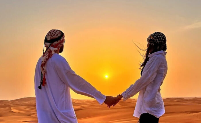 A couple stands hand in hand in a vast desert, enjoy private morning desert safari