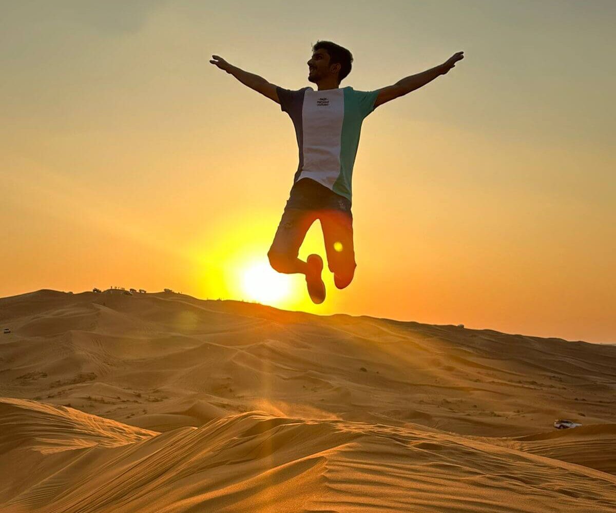 man jumping against a vibrant sunset in the desert